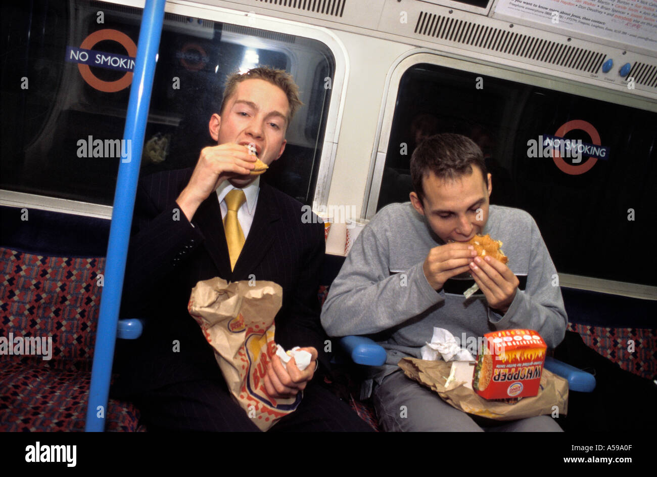 Young men eating fast food on the London underground England UK Stock Photo