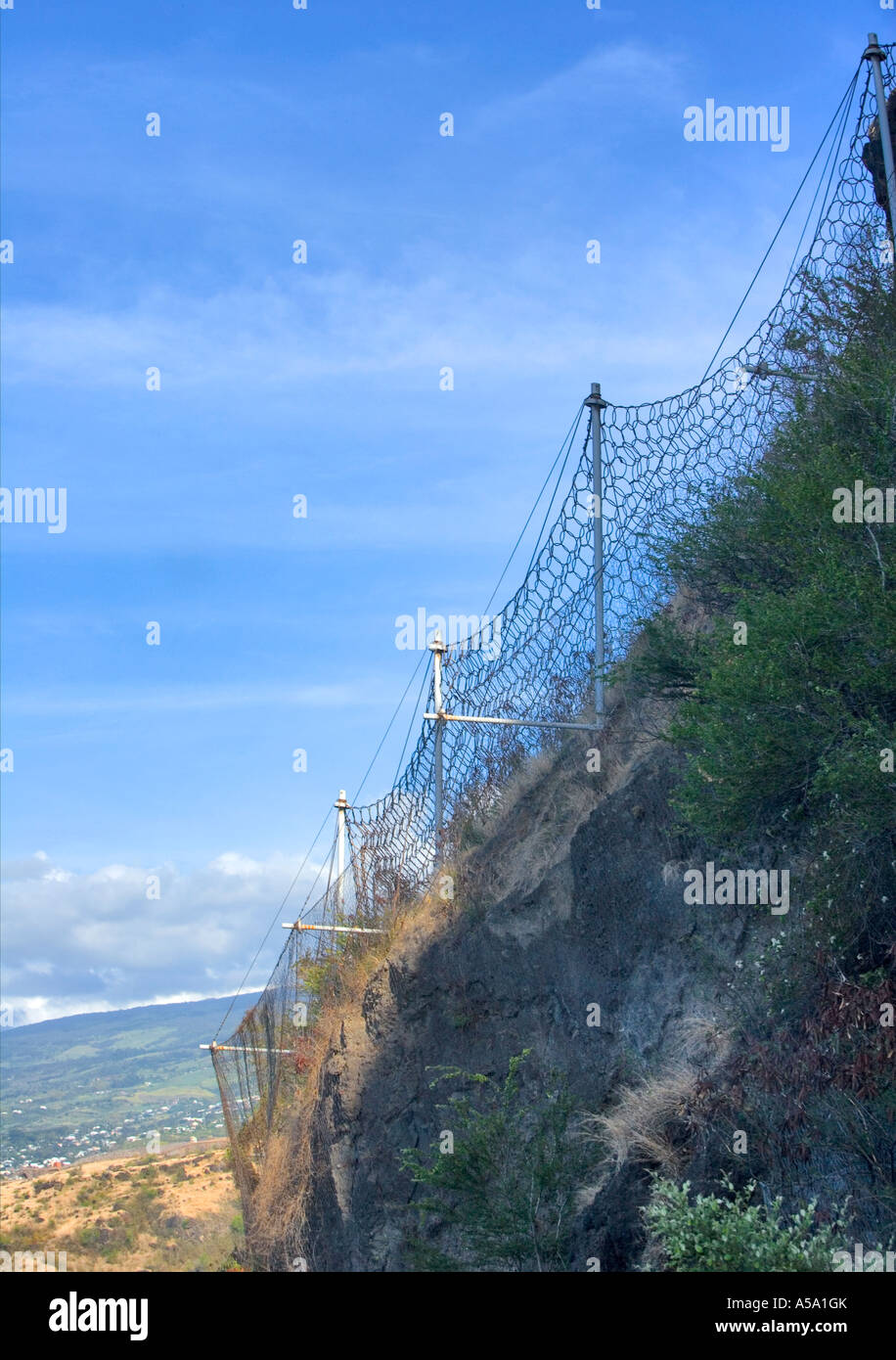 Defensive wire netting against rock fall dangers on coastal road in Réunion Stock Photo