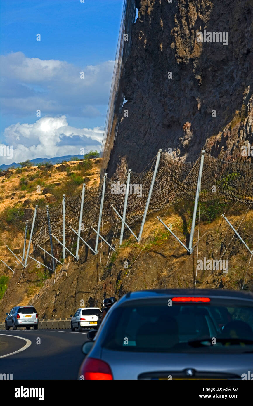 Defensive wire netting against rock fall dangers on coastal road - Réunion Stock Photo