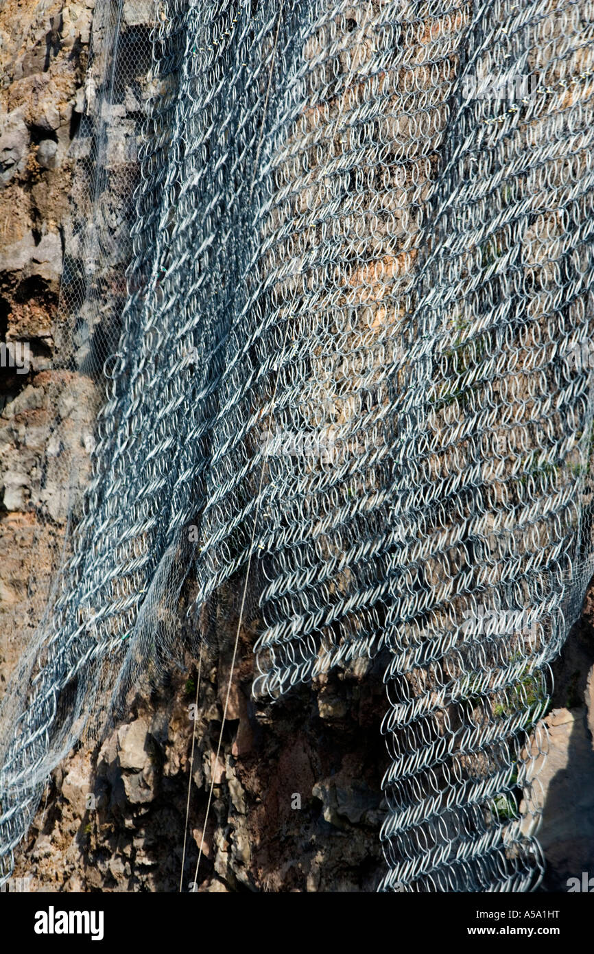 Defensive wire netting against rock falls danger on coastal road in Réunion Stock Photo