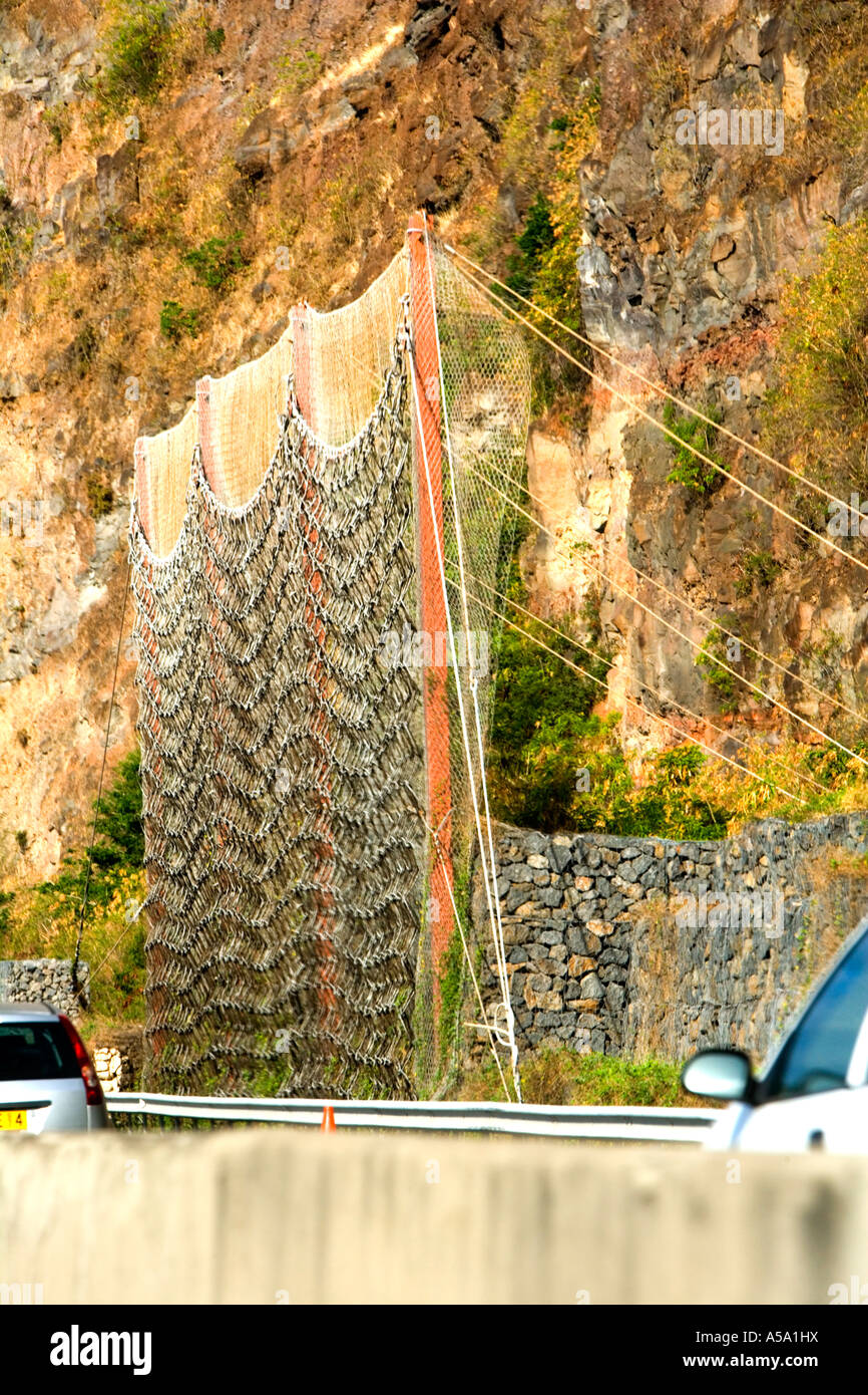 Defensive wire netting - a safeguard against dangerous rock falls on coastal road in Réunion Stock Photo