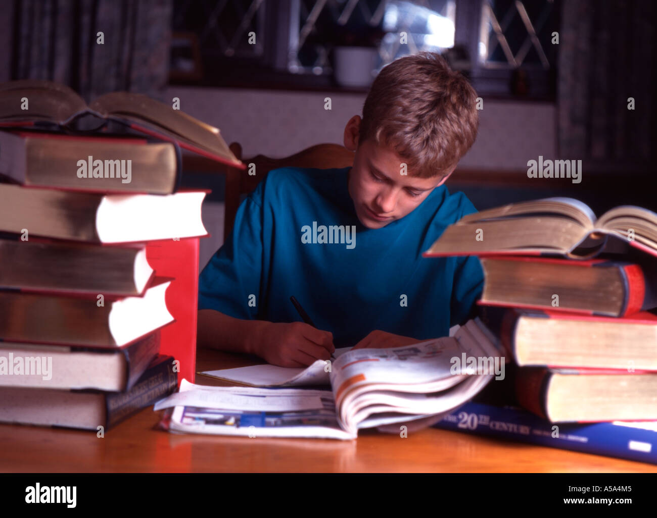 Child with many books working late into the night with his homework. Stock Photo