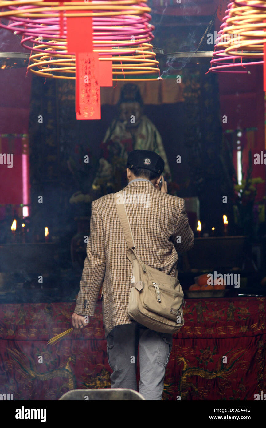 Hong Kong, Kowloon, Tin Hau Temple, Man on his cell phone offering incense, China Stock Photo