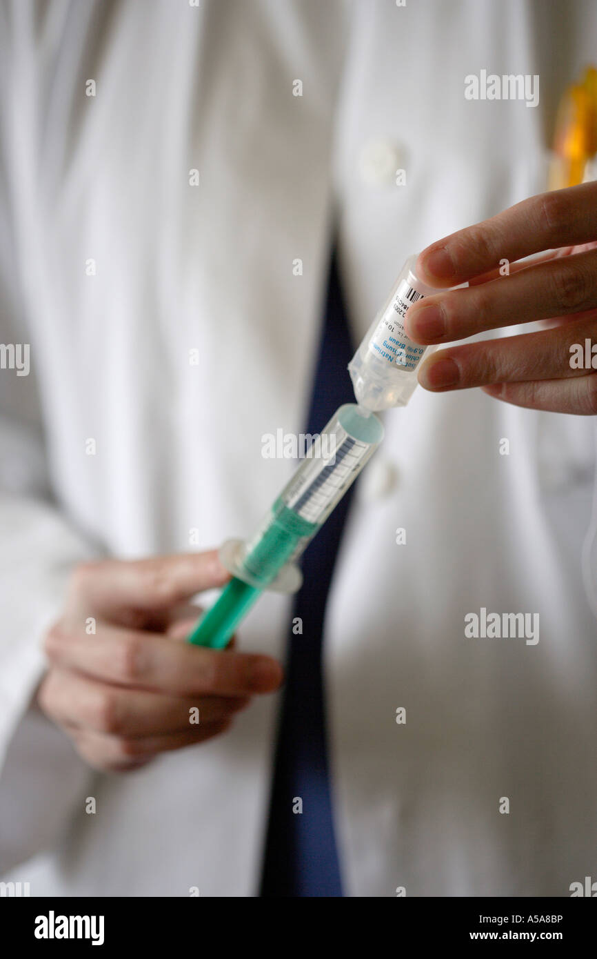 WOMAN DOCTOR PREPARES A SYRINGE FOR AN INJECTION Stock Photo