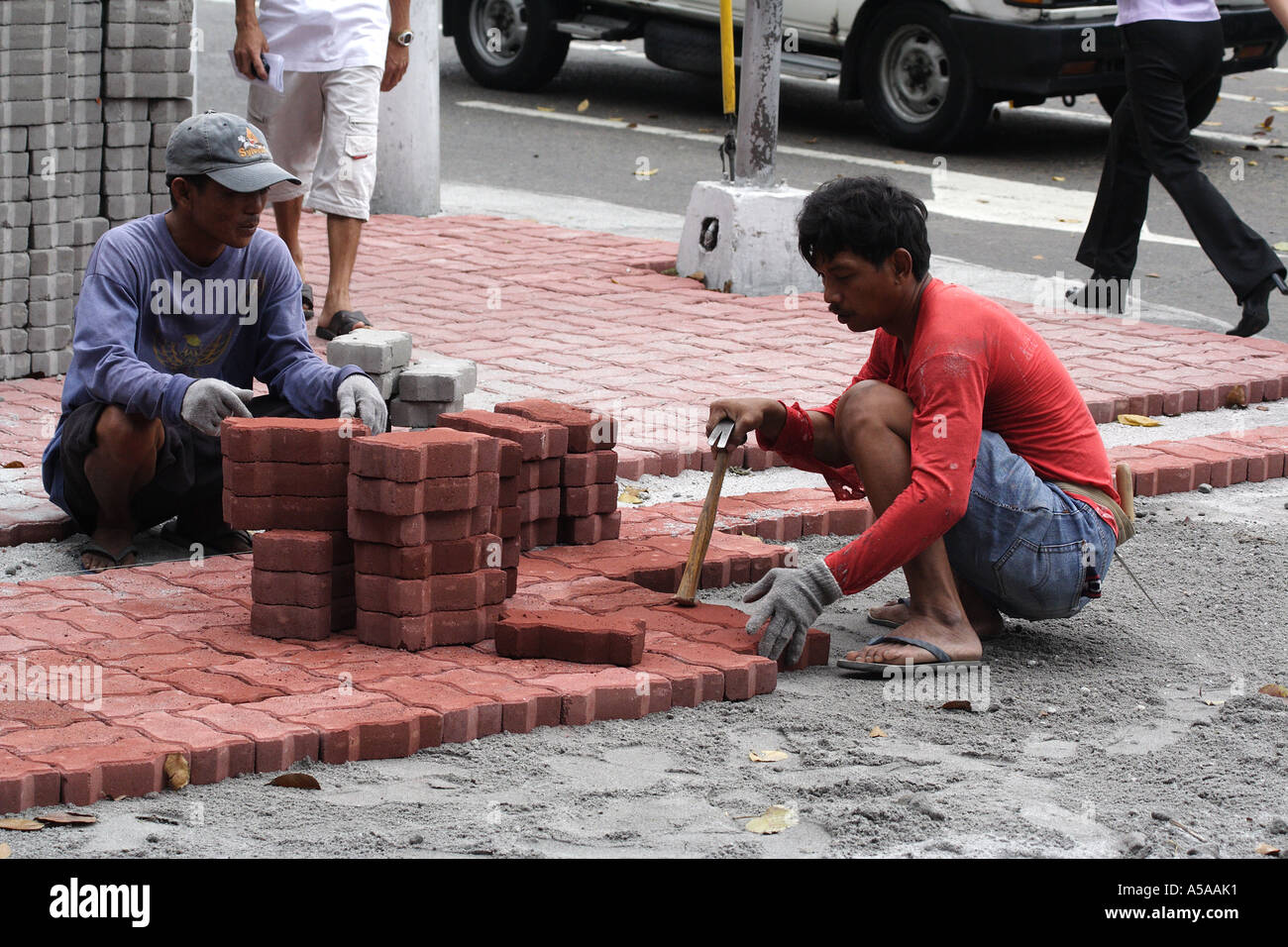 Workmen laying bricks for a walkway in Manila, Philippine Islands Stock