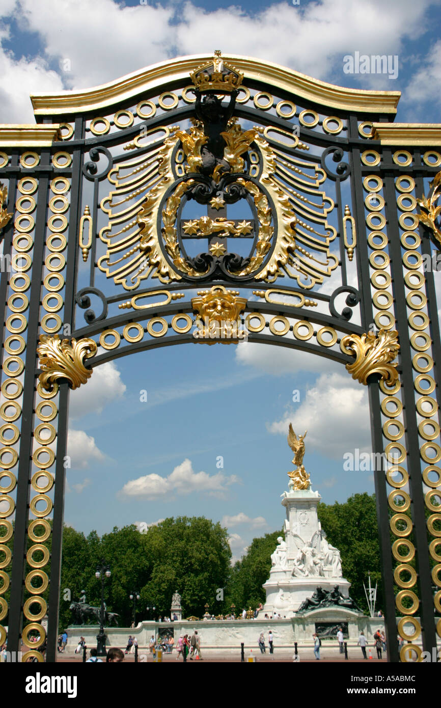 gold coloured metal gate by buckingham palace london england summer queen victoria fountain beyond Stock Photo