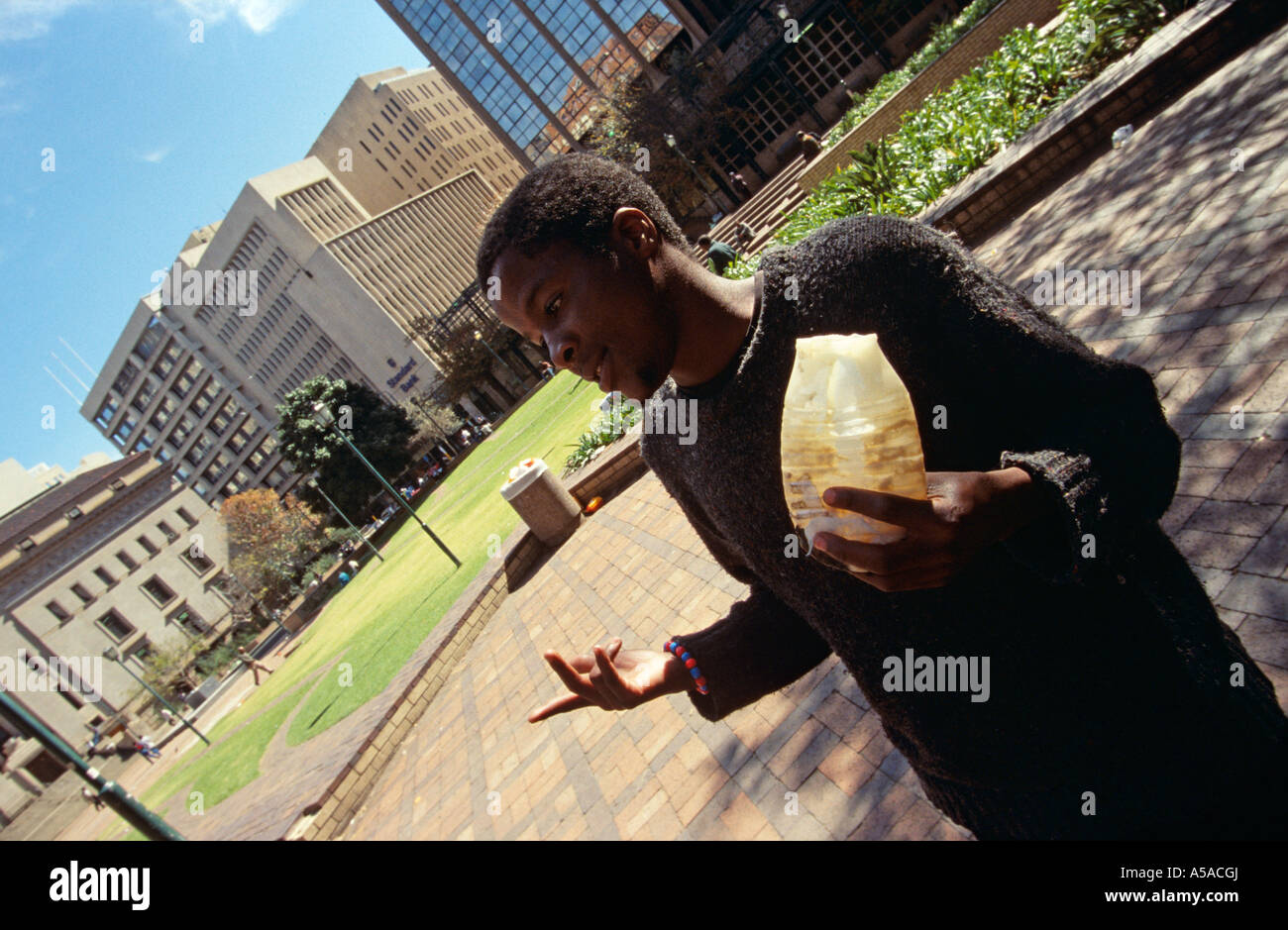 Young homeless boy sniffing glue on streets, Johannesburg, South Africa Stock Photo
