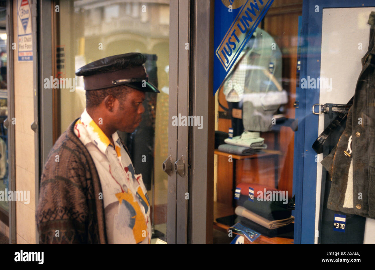 A man looking at clothings on display by a shop window Stock Photo