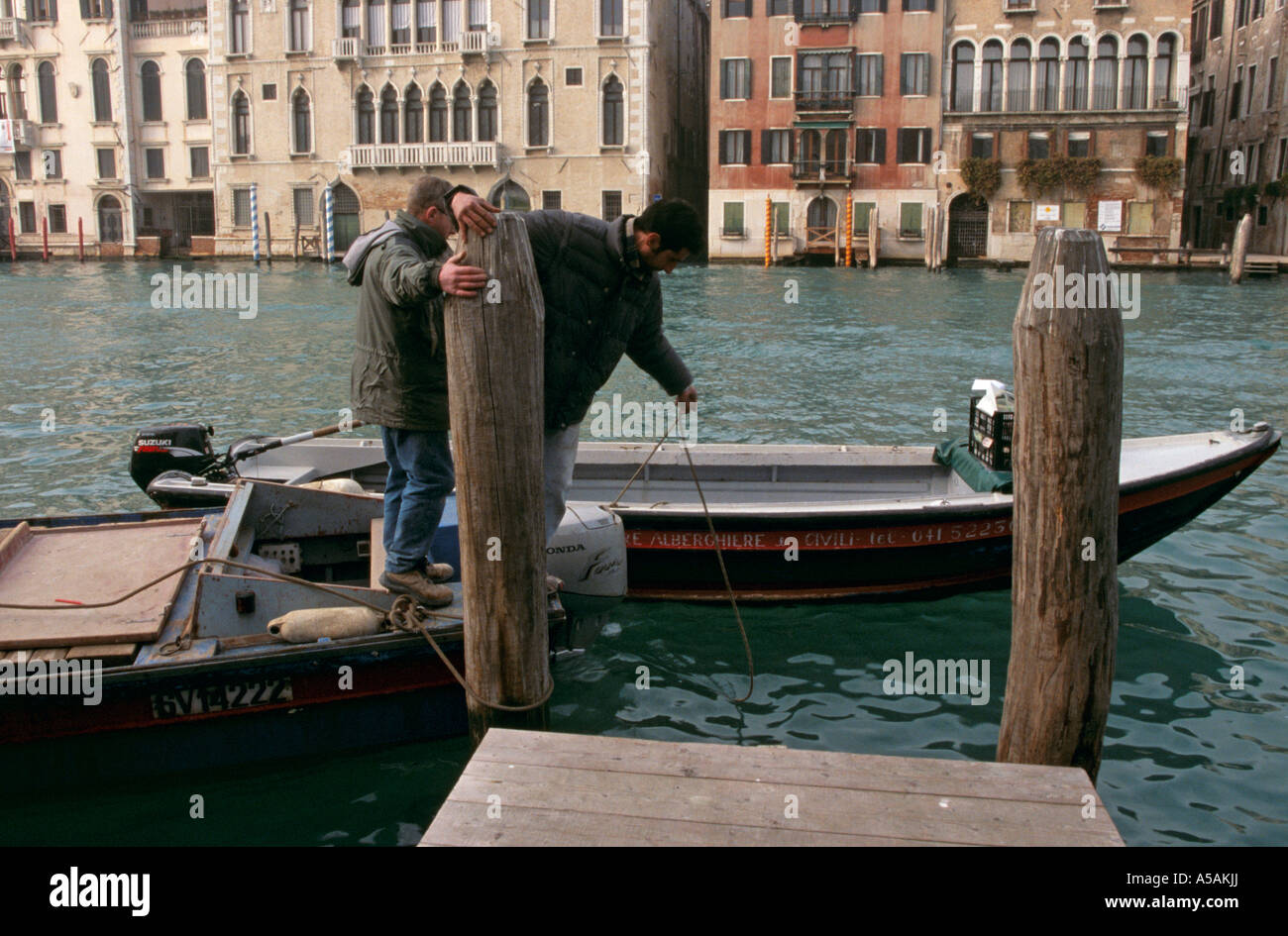 Men anchoring their boat on a canal in Venice Italy Stock Photo
