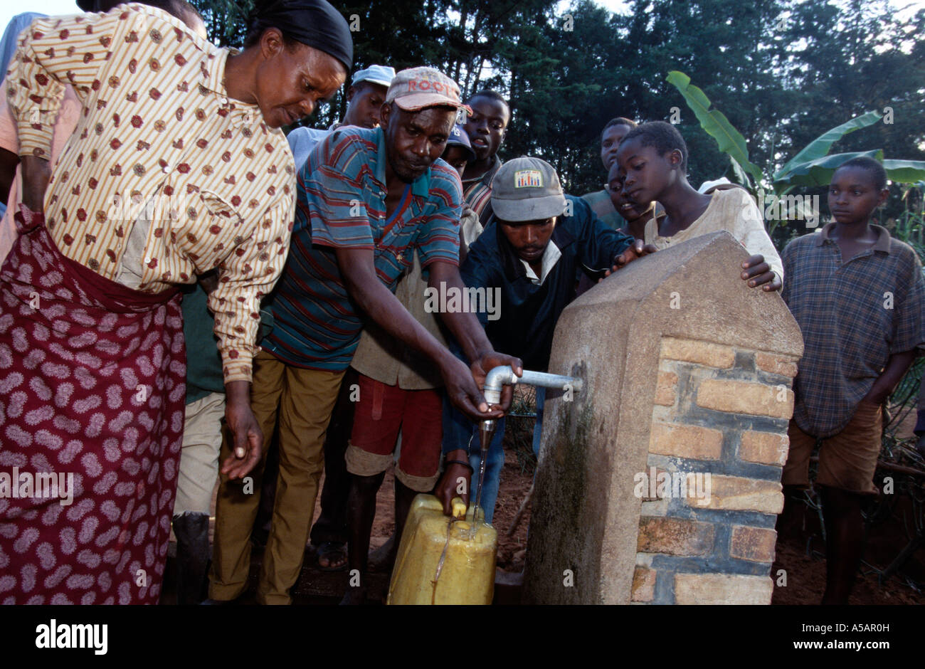 Villagers collecting water from communal water pipe, Africa Stock Photo
