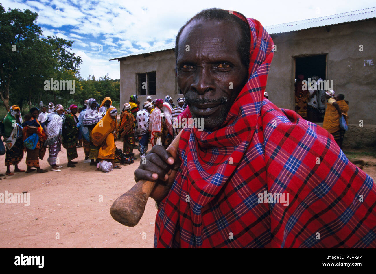 Portrait of man, villagers queueing in background, Nangwa, Tanzania, Africa Stock Photo