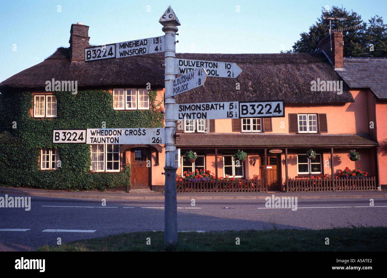 Signpost and thatched cottages in evening sunshine at the Exmoor village of Exford, Somerset, England Stock Photo