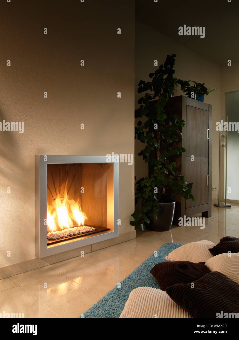 Modern style gas burning wall mounted fireplace in livingroom with tiled floor Stock Photo