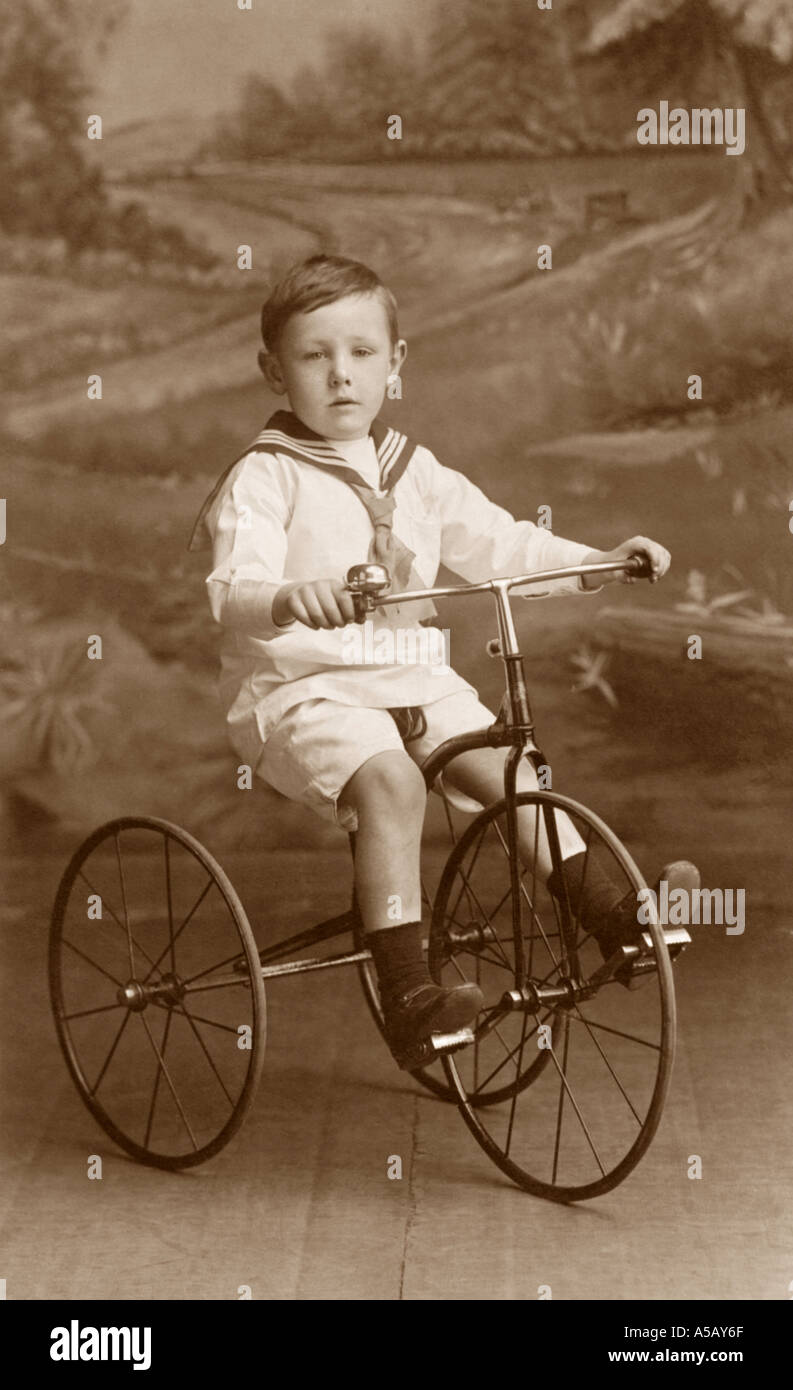 Original  WW1 era studio portrait of young boy wearing a sailor suit riding his toy tricycle, Rochdale, Greater Manchester, U.K., circa 1914 Stock Photo