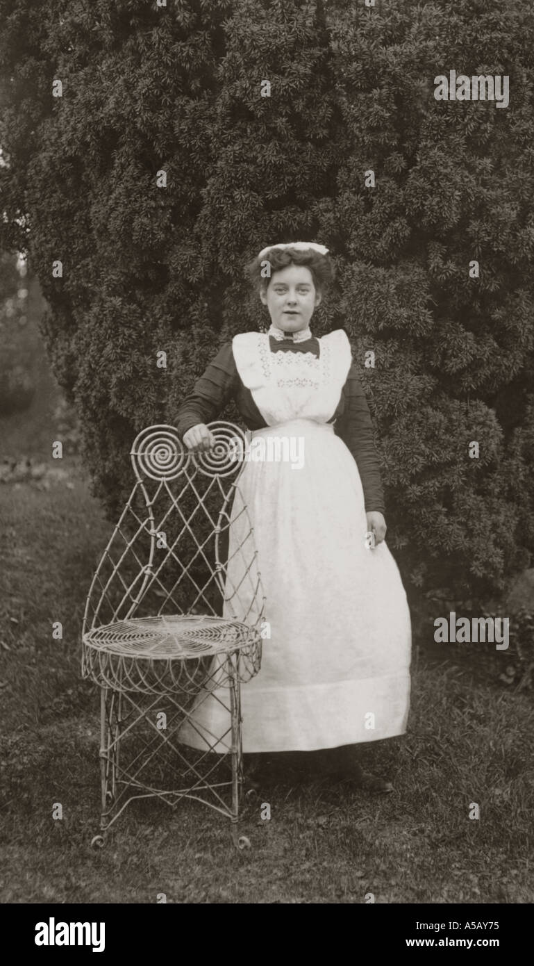 Original occupational portrait portraits postcard of Edwardian housemaid posing in garden of a country house next to chair, Cumbria, circa 1905, U.K. Stock Photo