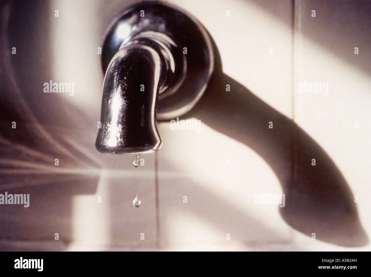 Water faucet with two drops of water dripping from the spigot into the