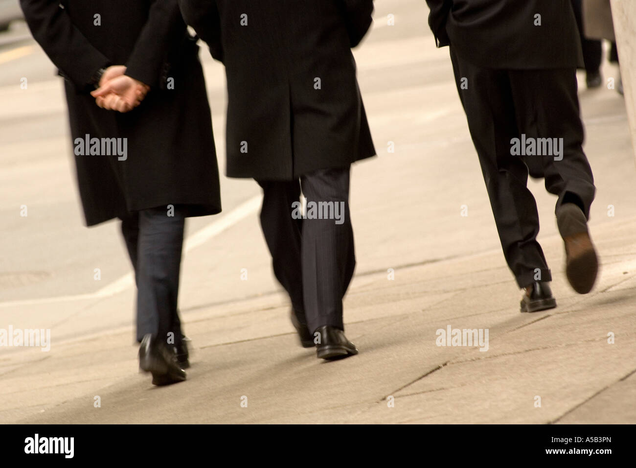 Three men walking downtown wearing black coats. Stock Photo