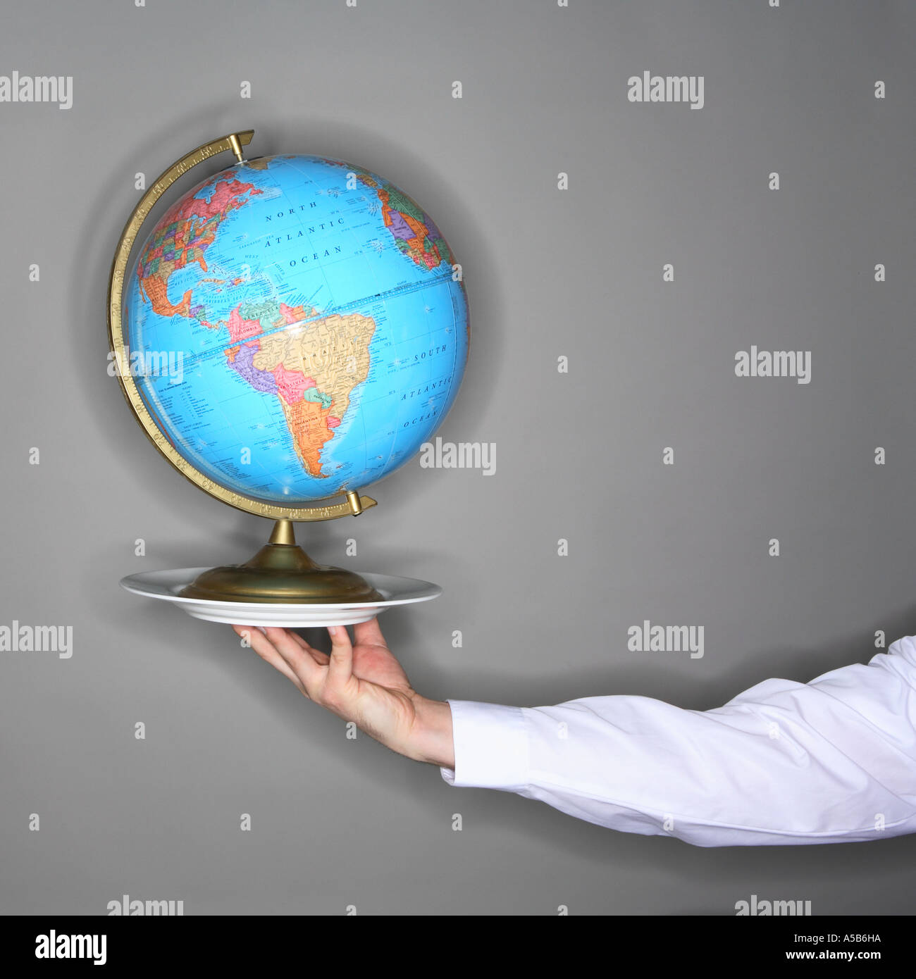 Arm holding globe on a plate Stock Photo
