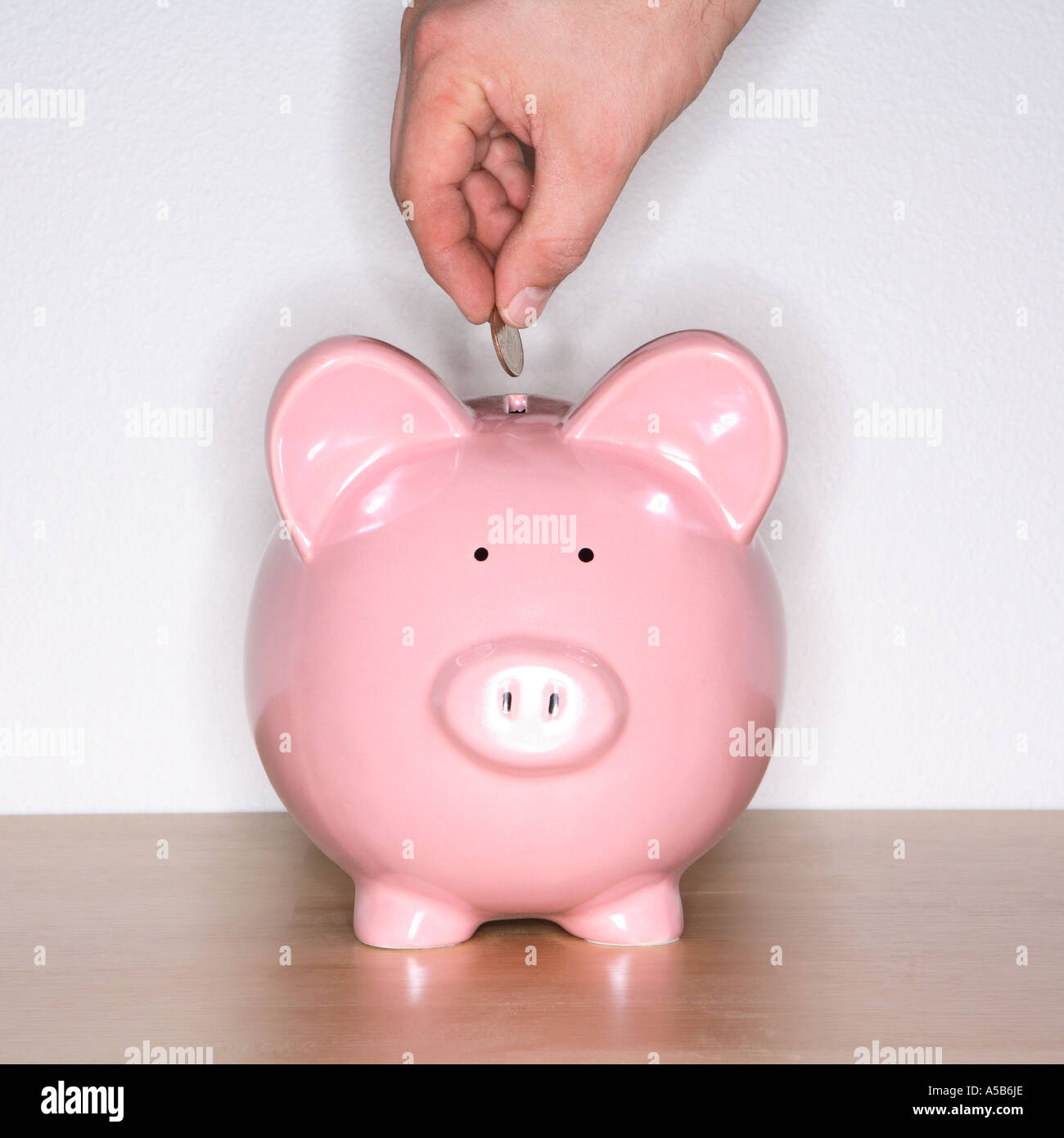 Hand putting coin in piggy bank Stock Photo