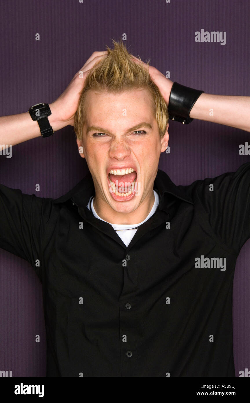 Young man with spiky hair posing and shouting in photo booth. Stock Photo