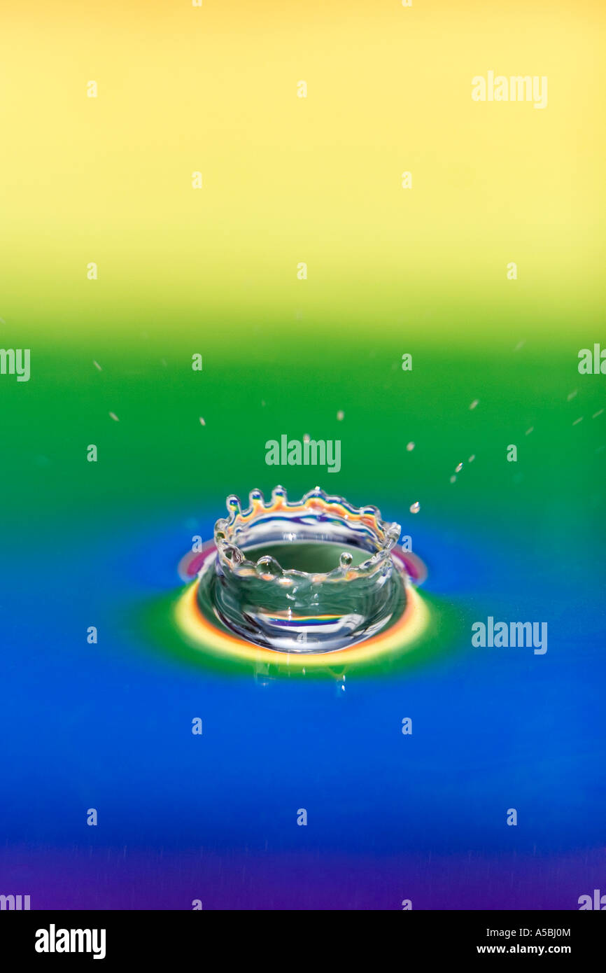 Coloured water drop splash. Water on a plate mirror with reflected colour background. Stock Photo
