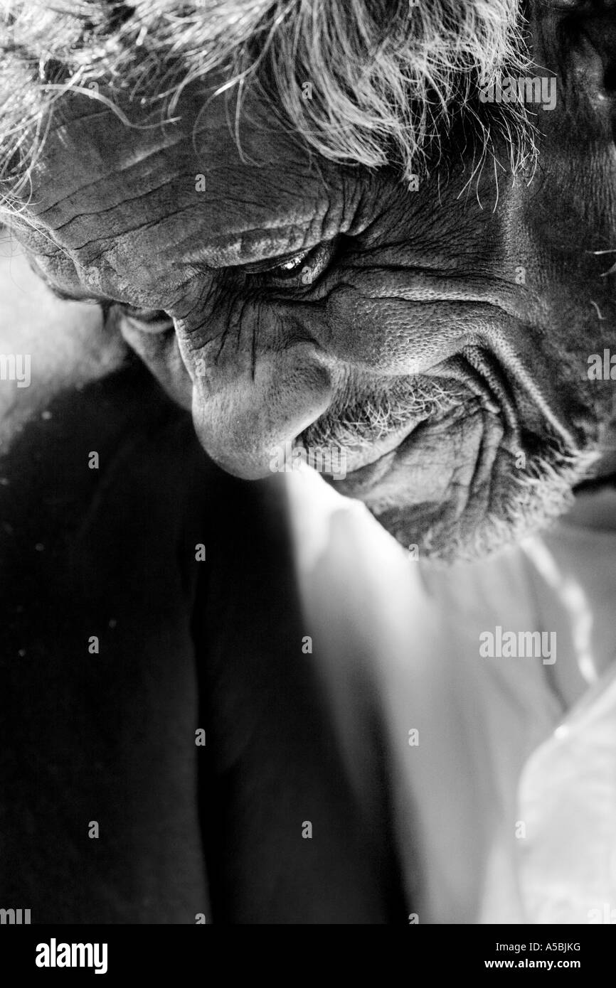 Old Indian village man staring into water with the light reflection on his face. Andhra Pradesh, India. Monochrome Stock Photo