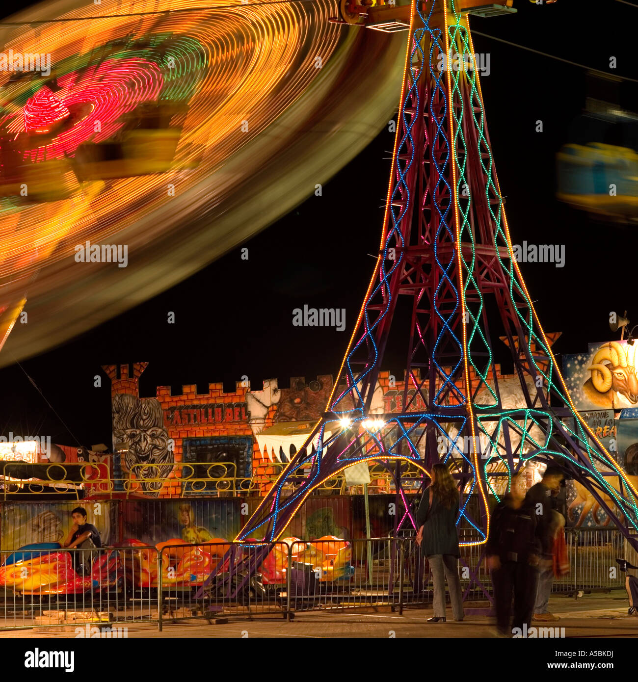 fairground spinning wheel at night time with Eiffel tower look alike pylon surreal weird unusual image concept Stock Photo