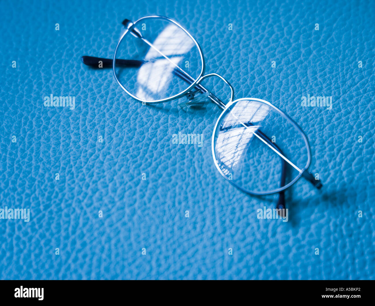 Reading glasses laying on blue mottled background Stock Photo