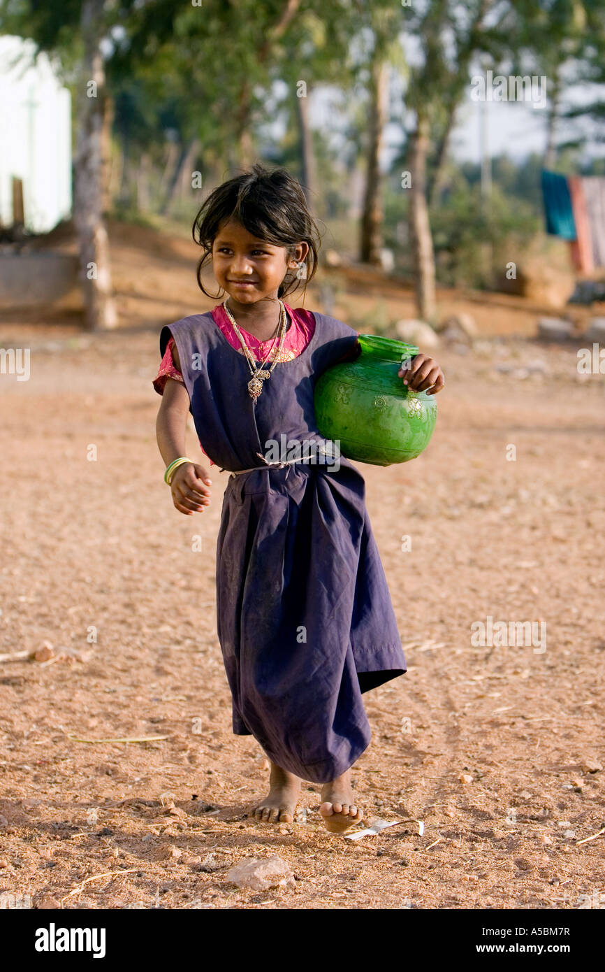 Young poor Indian girl carrying water pot from a village water tap