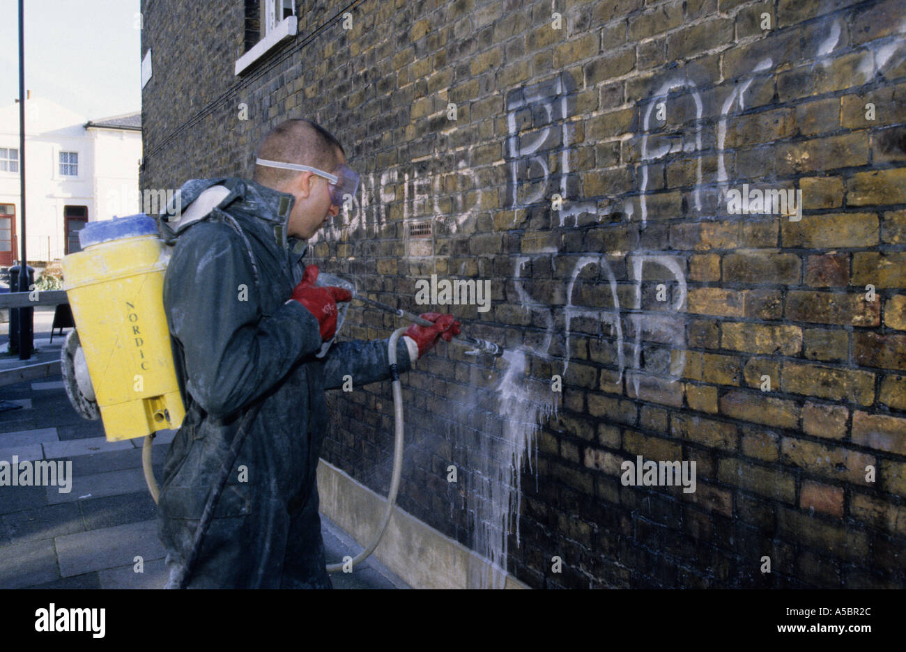 Council contractor removing graffiti from a wall in Greenwich London, England, UK Stock Photo