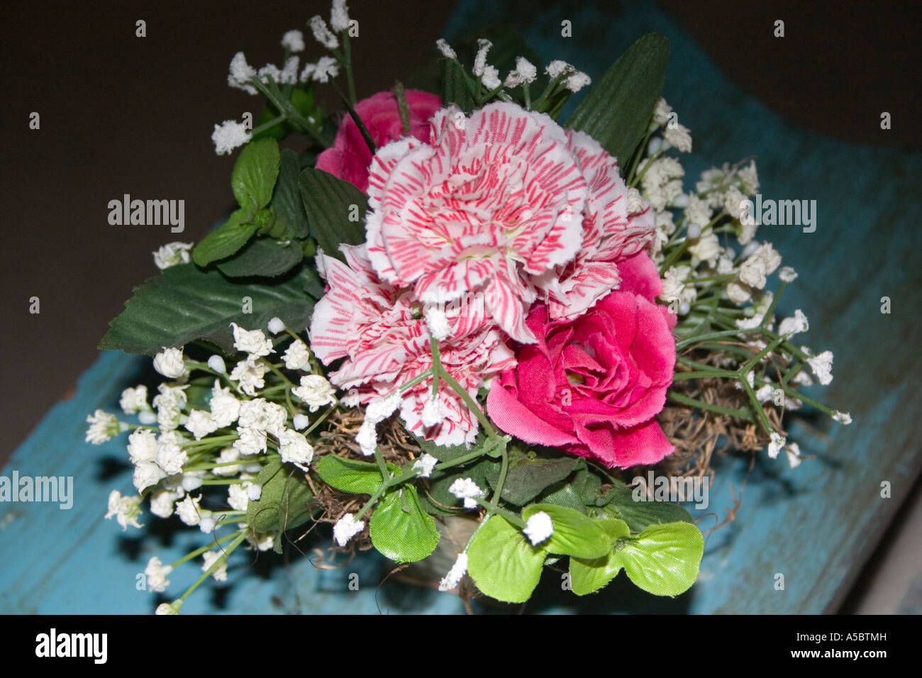 Artificial bouquet of carnation and rose flowers sitting on deck bench. Plymouth Minnesota USA Stock Photo