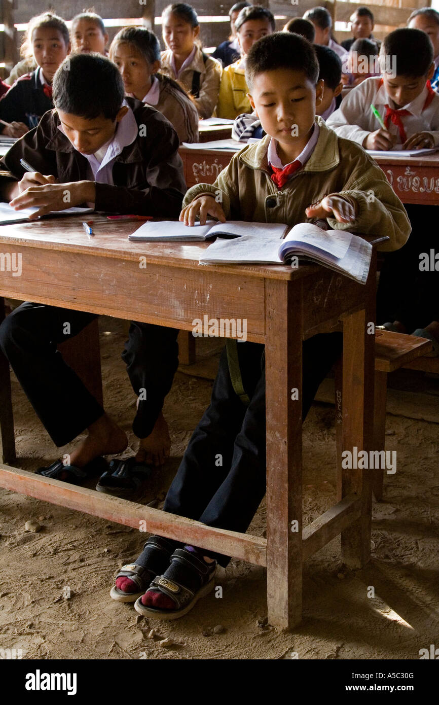 Boys Writing at Desk in Dirt Floor Classroom Hongsa Laos Stock Photo