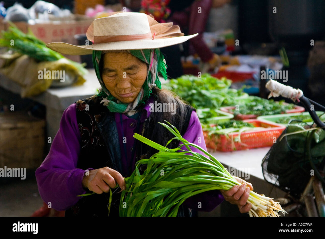 Ethnic Minority Woman Inspecting Green Onions at Market Menghai China Xishuangbanna Stock Photo