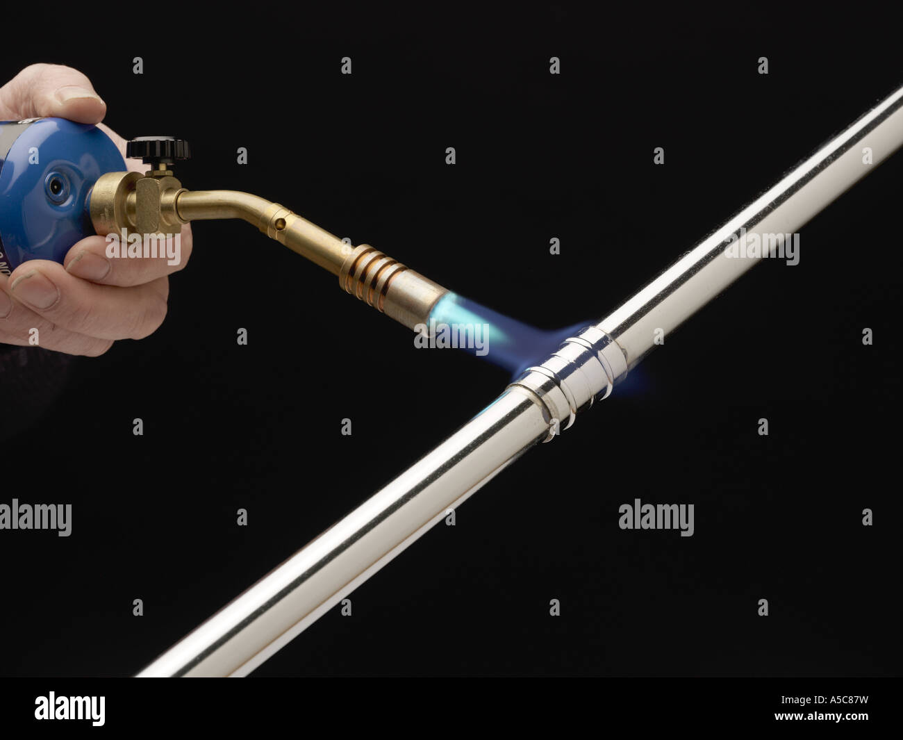 Hand holding a Gas Blow Torch heating up a Yorkshire Fitting on a 15mm