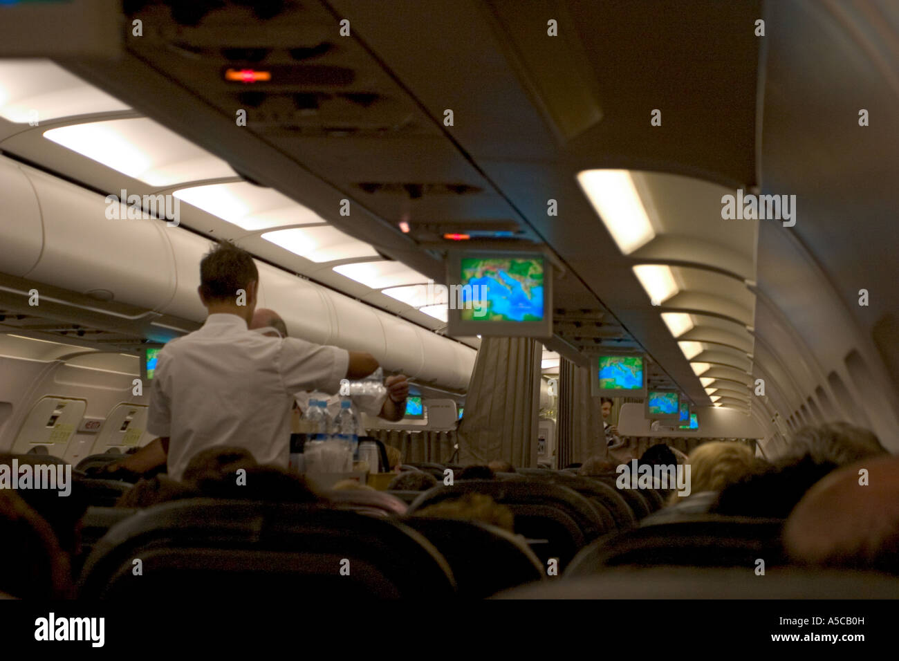 inside airplane and mini tv monitor with steward crew members Stock Photo