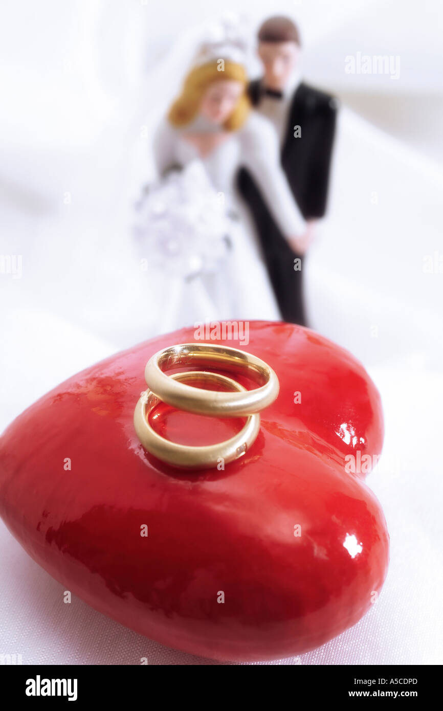 Bride and groom figurines with wedding rings on heart Stock Photo