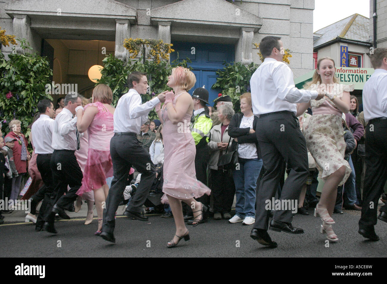 Young men and women dance out of the Town Hall at the start of the Early Morning Dance on Helston's Flora Day Stock Photo