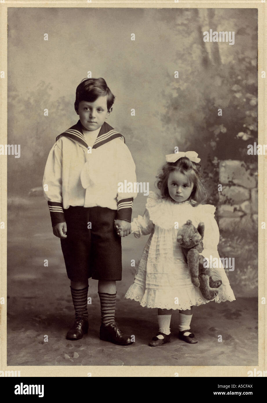 Studio portrait photo of Edwardian girl and boy with a teddy bear, UK. circa 1910 Stock Photo