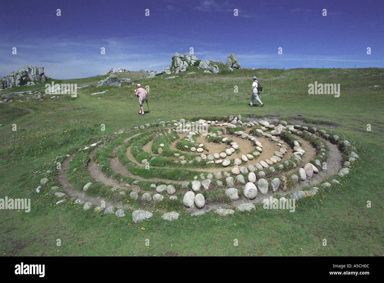 Walkers passing Troy Town Maze on the island of St Agnes Isles of Scilly built around 200 years ago Stock Photo