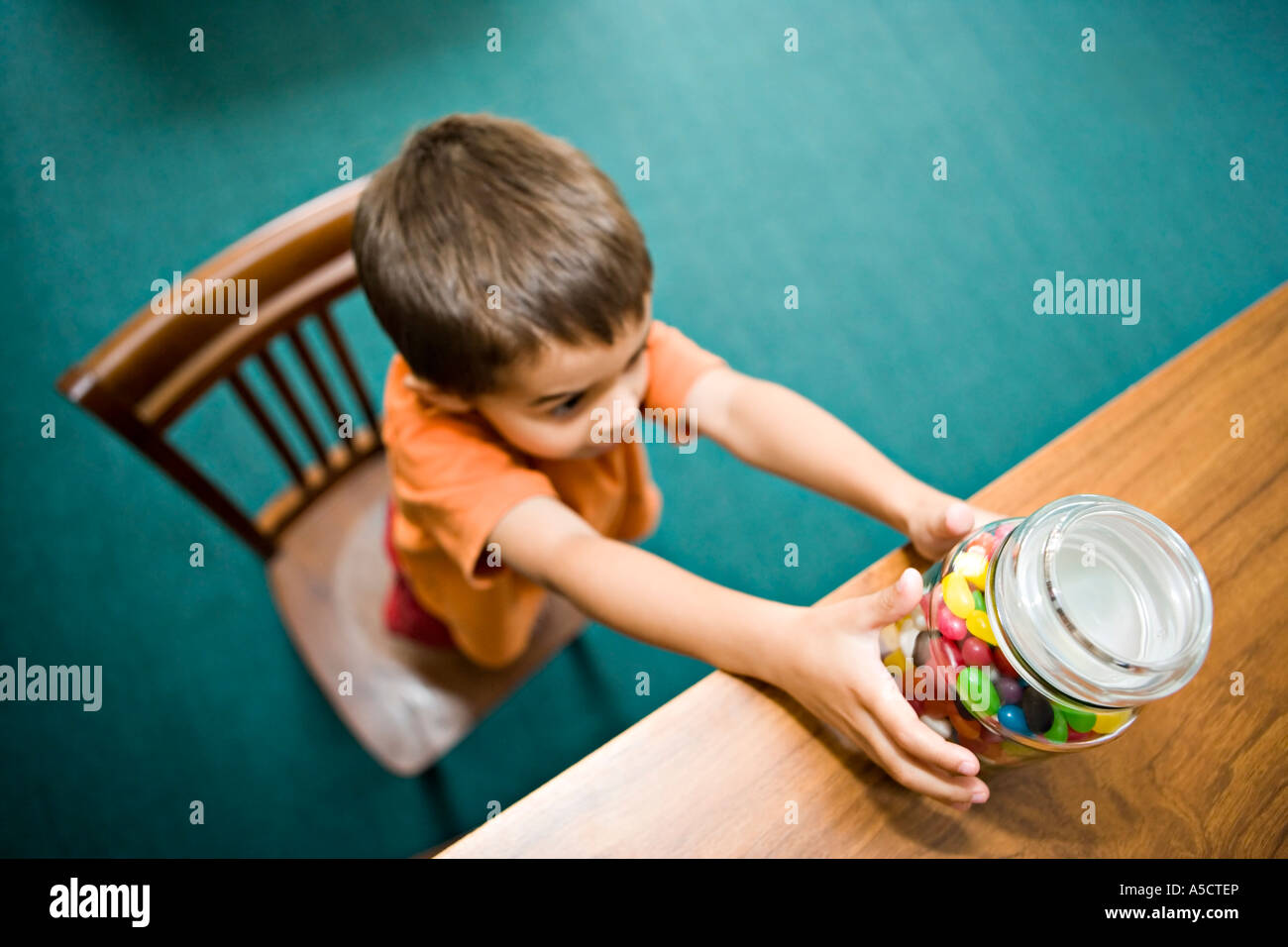 Looking down on boy reaching for sweet jar Stock Photo