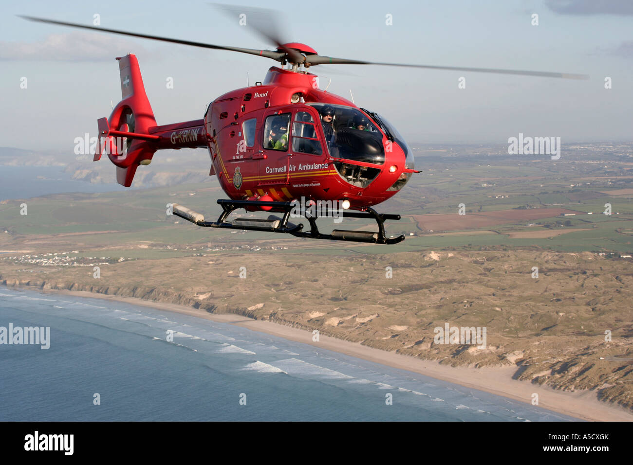 Air to air photograph of Newquay based Cornwall EC135 Air Ambulance over beach Stock Photo
