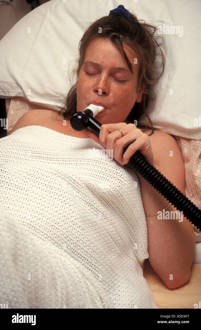 young labouring mother using gas and air mouthpiece for pain relief Stock Photo