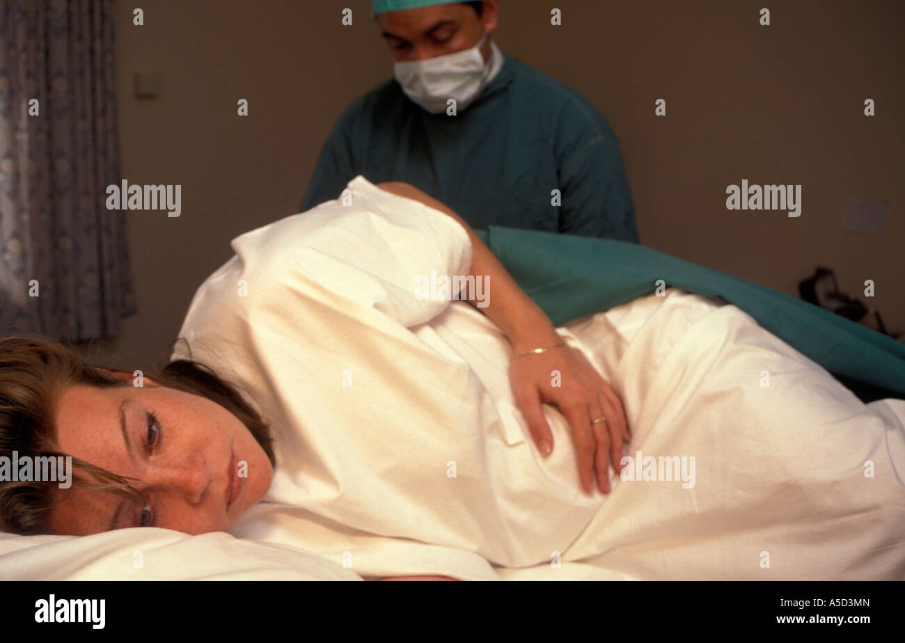 Anaesthetist preparing young pregnant mother for epidural Stock Photo