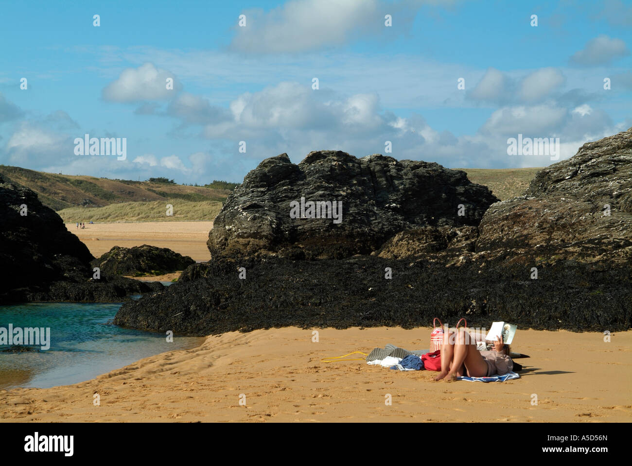 Woman reading and tanning on a sandy beach on Belle Ile en Mer Stock Photo