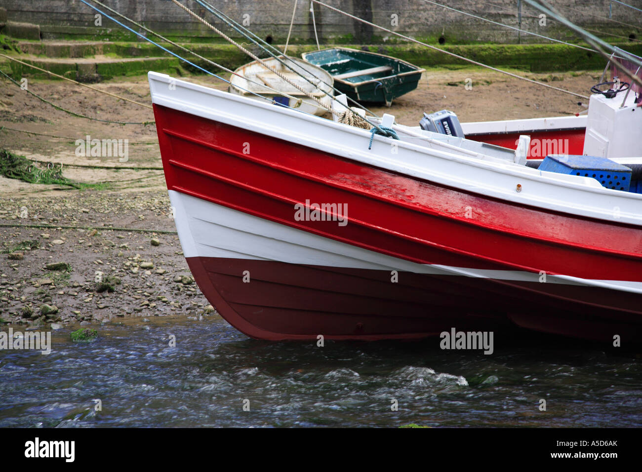 Red fishing boat moored up in Staithes Harbour Stock Photo