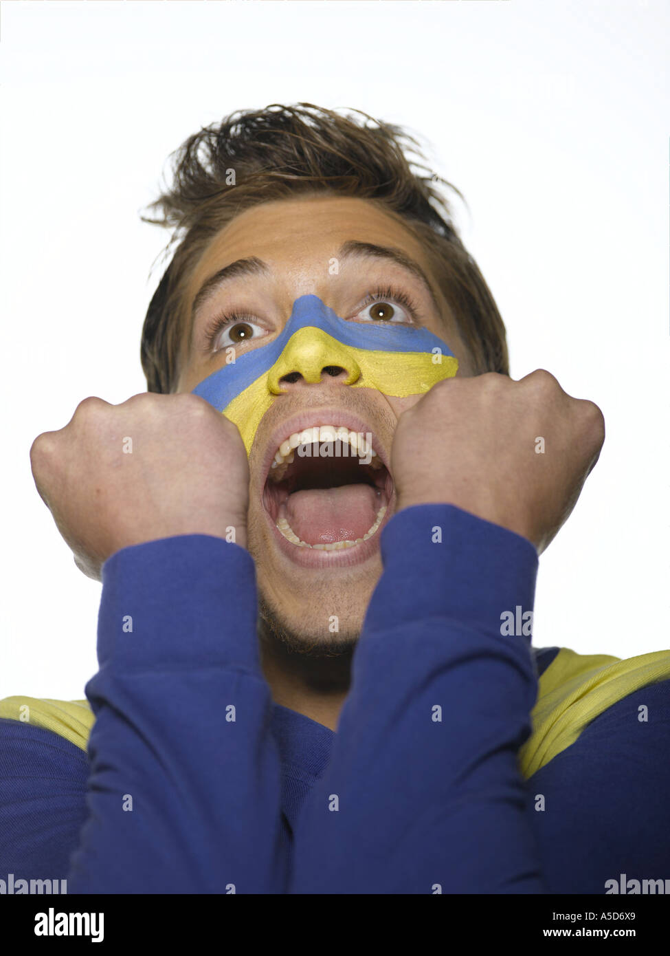 Young man with Ukrainian flag painted on face, mouth open, looking up, close-up Stock Photo
