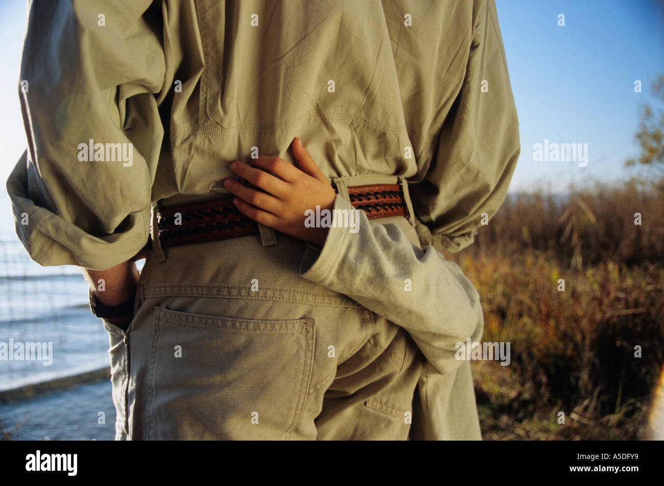 Father and son by lake, mid-section, rear view Stock Photo