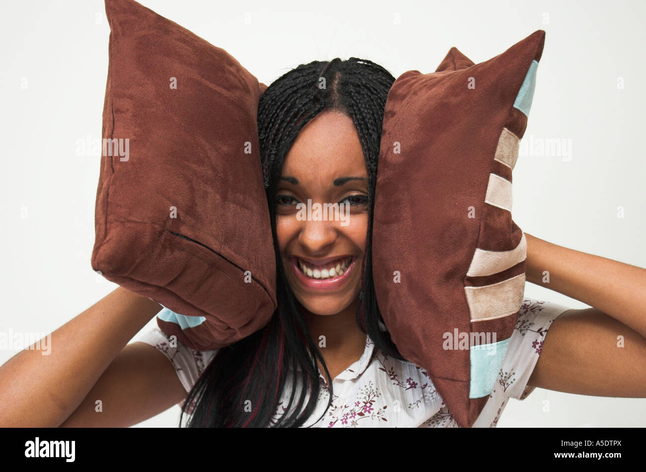 Young mixed race woman holding cushions over her ears trying to block out annoying or distracting sound. Stock Photo