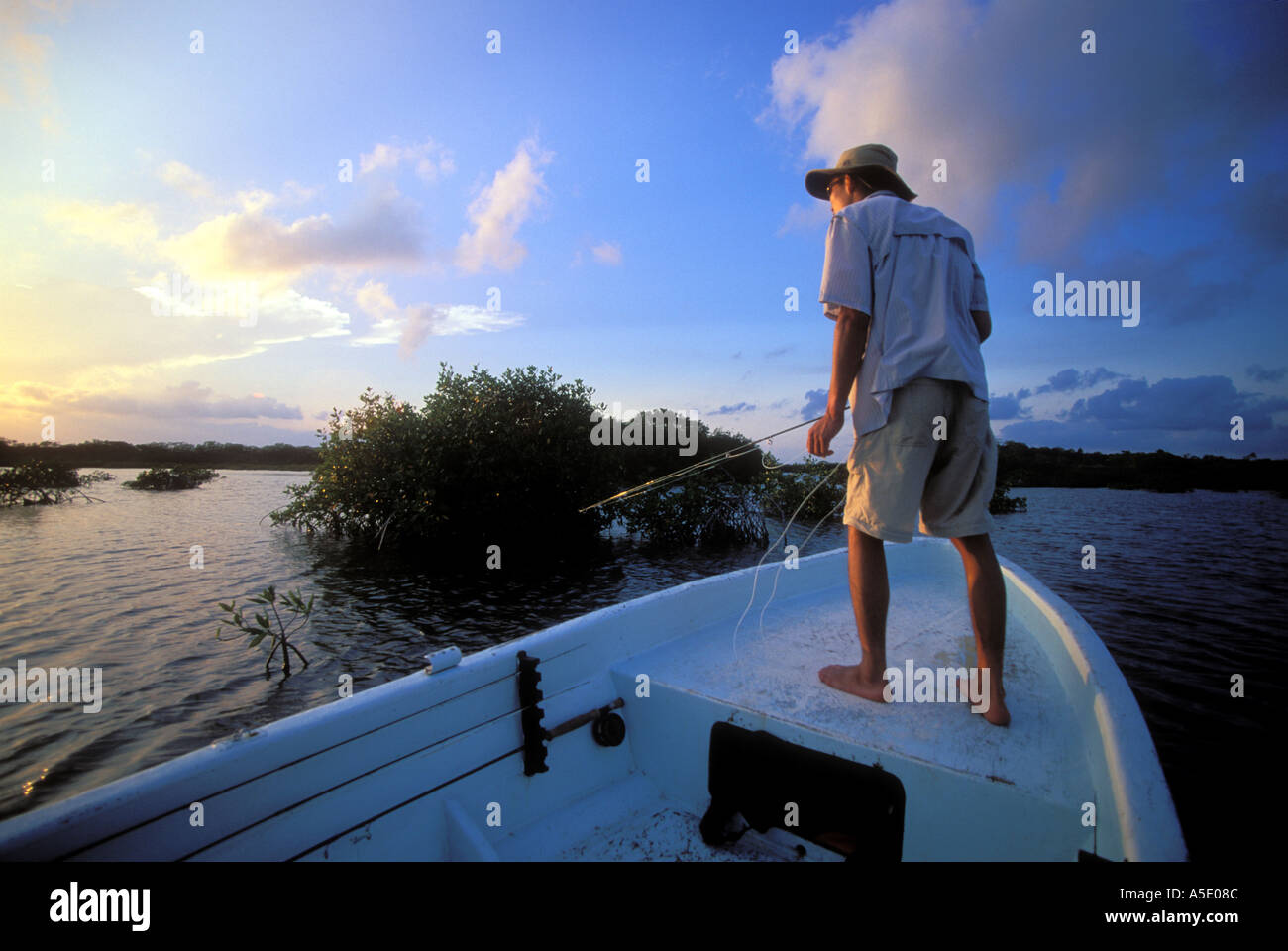 Fly fisherman standing on bow of boat ready to cast Belize Central America Caribbean Stock Photo