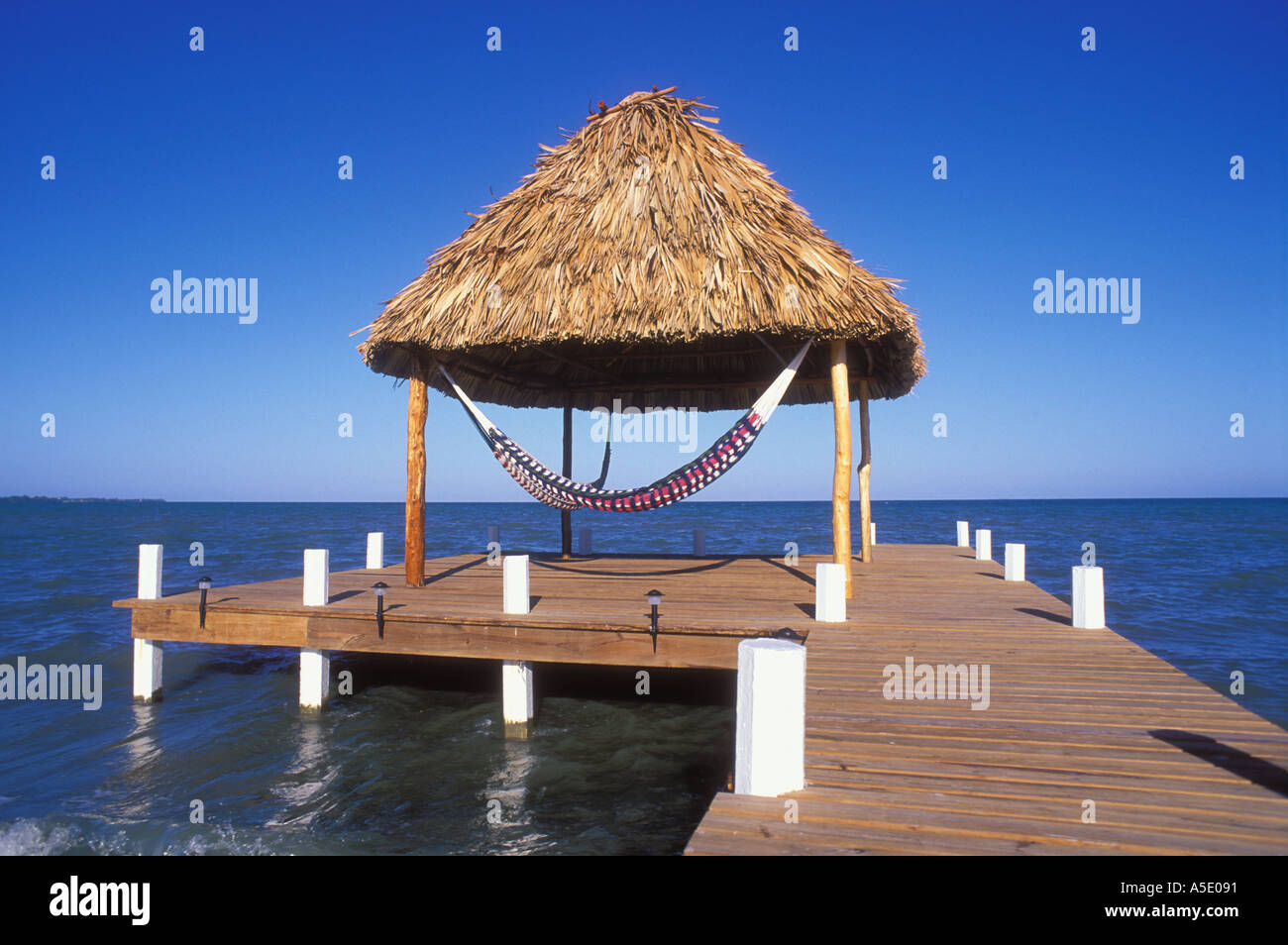 Dock over water with thatched shade and hammock Belize Central America Caribbean Stock Photo